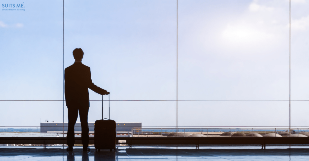 Man looking out of an airport window, representing moving to a new country