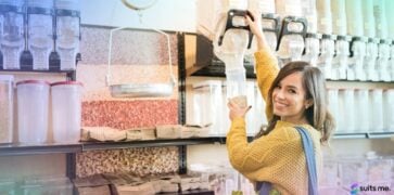 Happy Young Woman Bulk Buying Products for her Food Cupboard by Pouring Grains into a Reusable Container