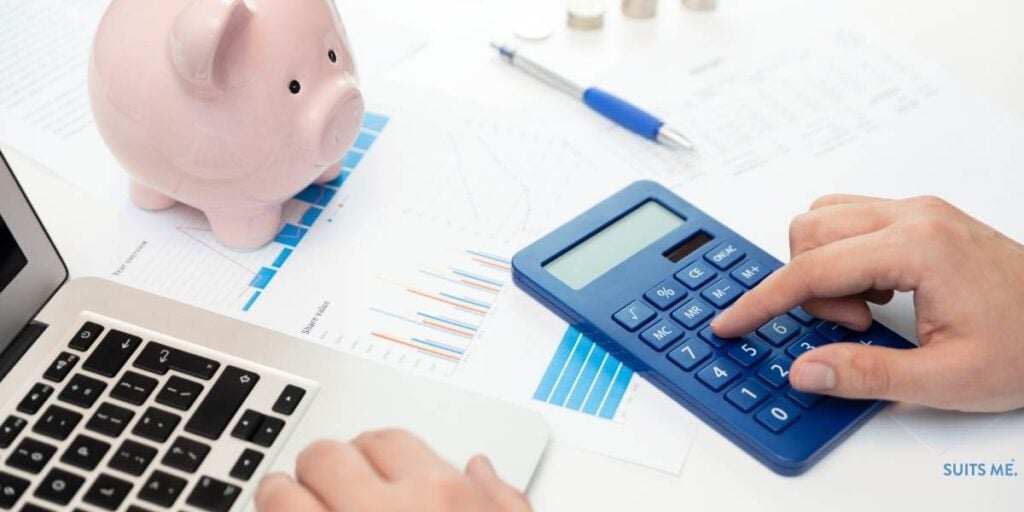 Man sat at table with laptop and piggy bank calculating his expenses. Budgeting Planning Concept