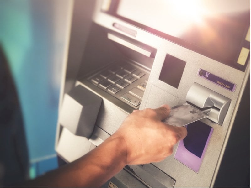 person inserting their debit card into an ATM Cash Machine