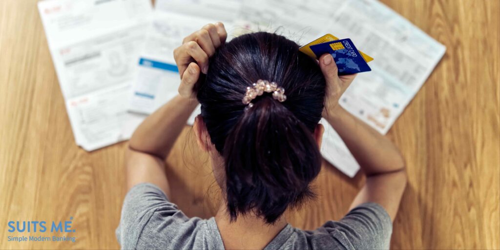 Top view of stressed young woman with her hands holding her head worried about  her credit score and debit card payments. Financial problems concept