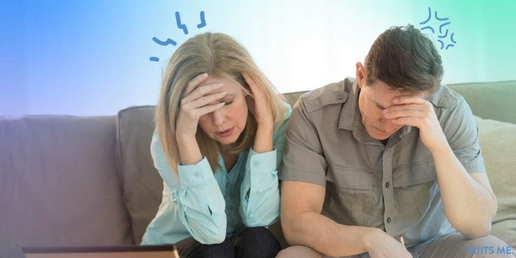 Man and woman sat in a couch looking at their finances and feeling stressed and worried about their financial future due to being stuck with outstanding debts