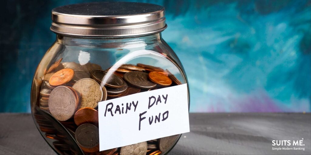 Words RAINY DAY FUND on label on clear glass jar filled with coins. Saving money concept.