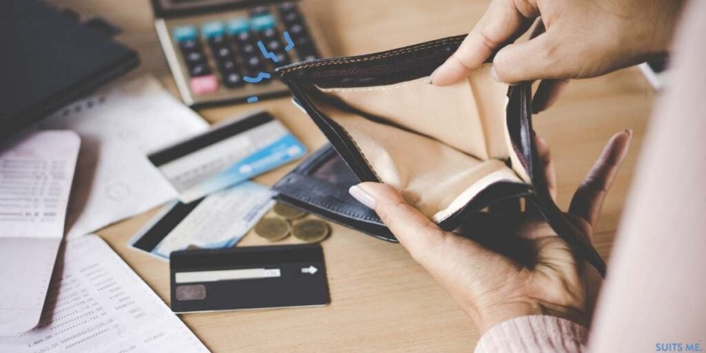 Woman looking through empty purse with a maxed out credit cards and a calculator - representing what it's like to be a victim of financial abuse