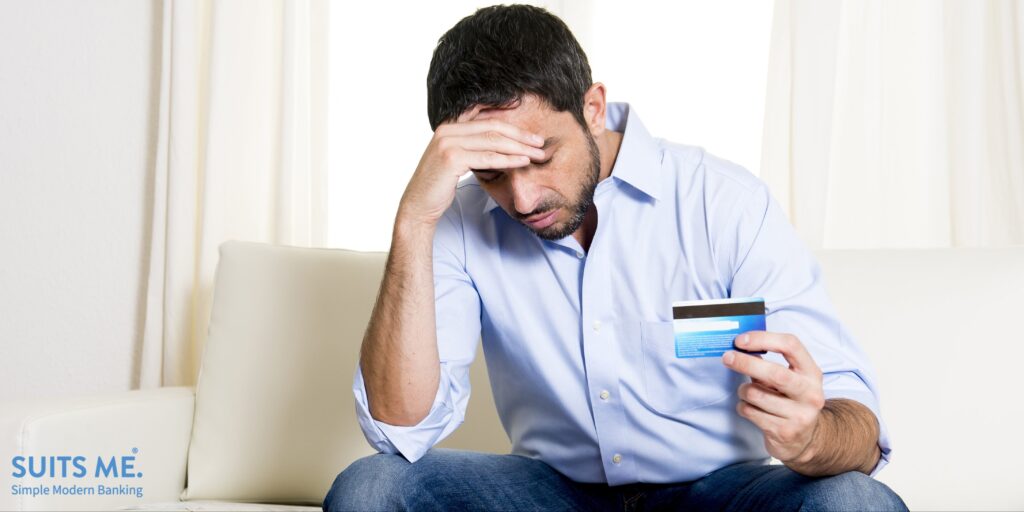 young business man at home sitting on sofa with debit card and calculator accounting costs, charges, taxes and mortgage for paying bills looking anxious and stressed