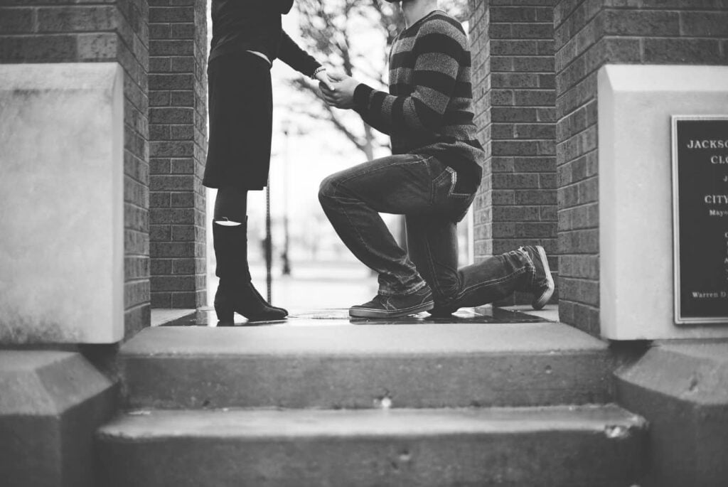 Man on one knee proposing to woman with an engagement ring