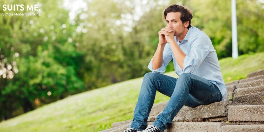 adult man in blue shirt sitting alone on stairs outside and thinking about finding proof of address to open a bank account