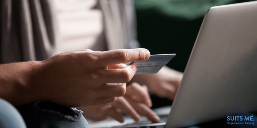 customers making secure payment on laptop via e-banking service, close up view of hand holding prepaid card