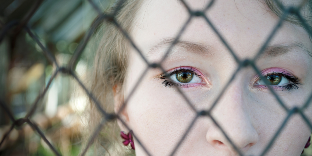 woman looking through metal fence