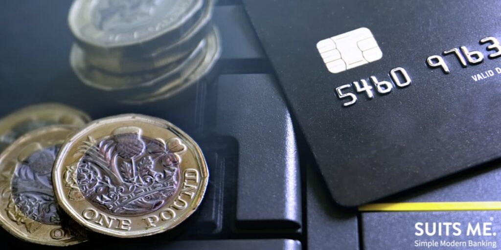 Prepaid card on a laptop keyboard next to new pound coins (GBP)