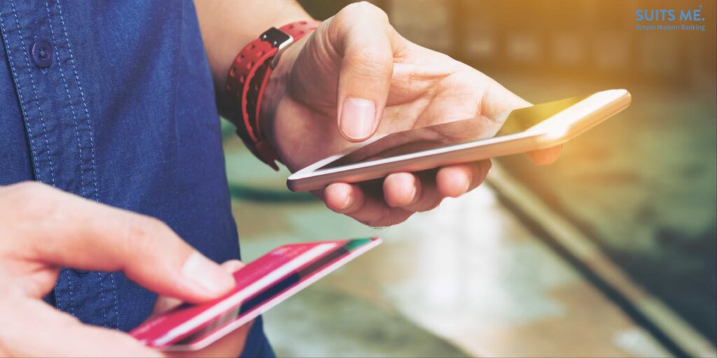 Person in denim shirt, holding prepaid card and mobile smartphone - representing a busy on the go lifestyle of a freelancer