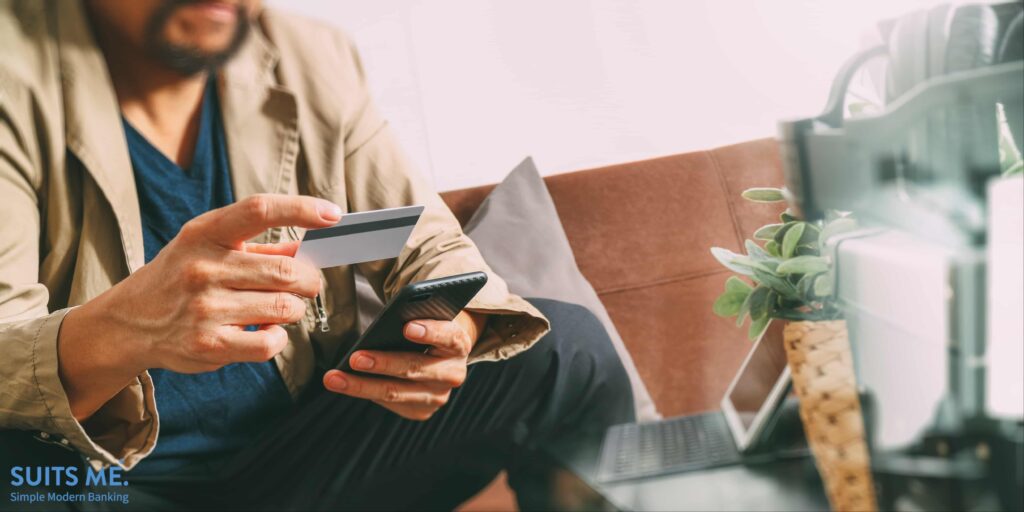 Man using digital banking on smart phone and holding debit card and making payments online