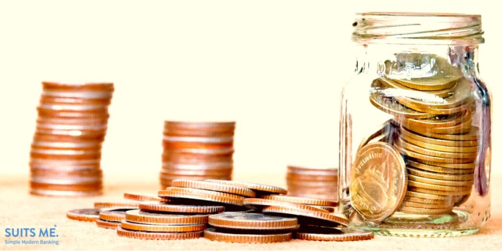 Glass Jar with Coins with smaller value coins scattered around on vintage blurred background - Saving money concept