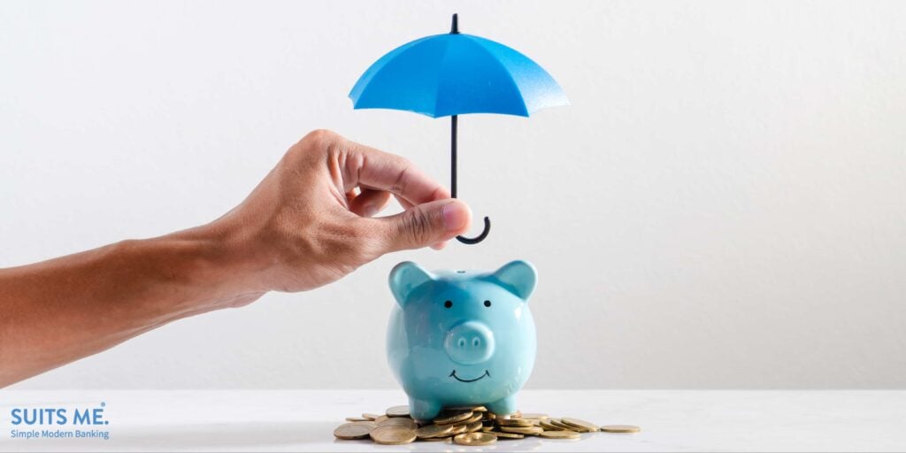 Blue piggy bank with a man holding an umbrella over it - representing creating an emergency fund or rainy day fund