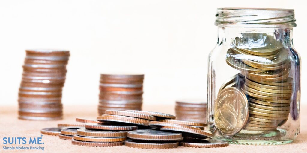 Glass of coin and four pole range of coins on vintage blurred background - Saving money concept,