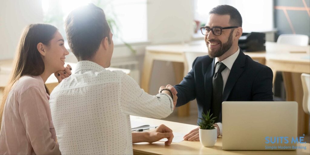 financial advisor handshaking with young couple who are thanking for advice on debt management