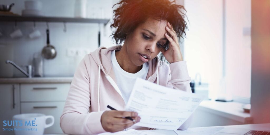 Young upset african american female sitting at kitchen table with laptop, dealing with financial stress, feeling pressure because of mortgage debt, worrying a lot or feeling anxious over money