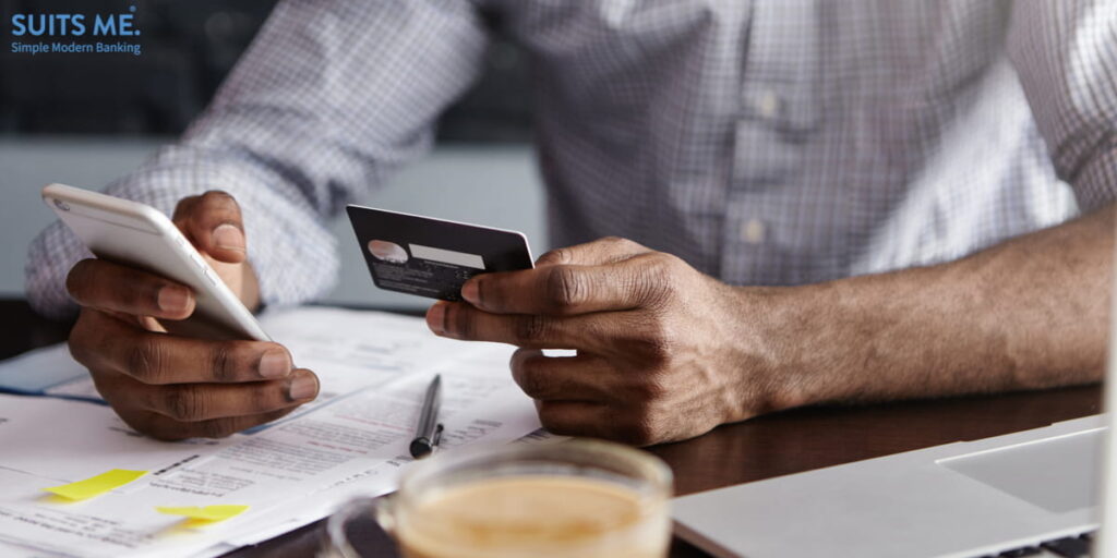 Businessman checking current account balance using online banking application on his smartphone, whilst drinking coffee at cafe