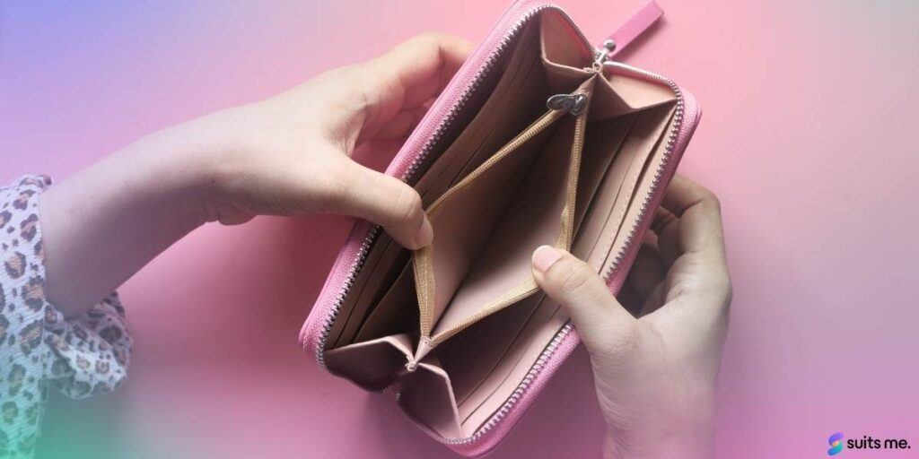 Birds eye view of a woman holding an Empty pink purse on a pink table. No money until payday concept. 