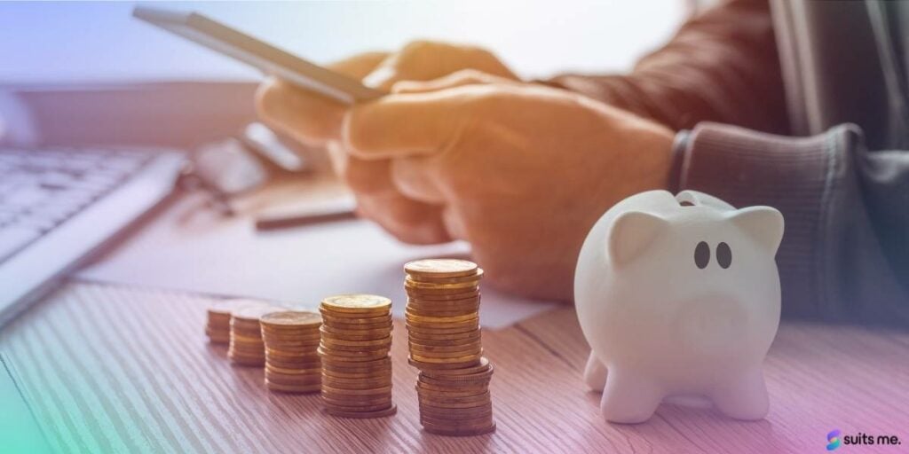 Man working out his budget on his phone with coins and a piggy bank 