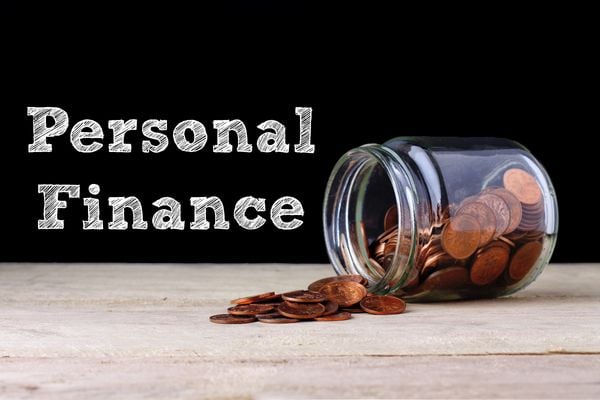 image of jar of coins tipped over and Personal Finance sign nest to it